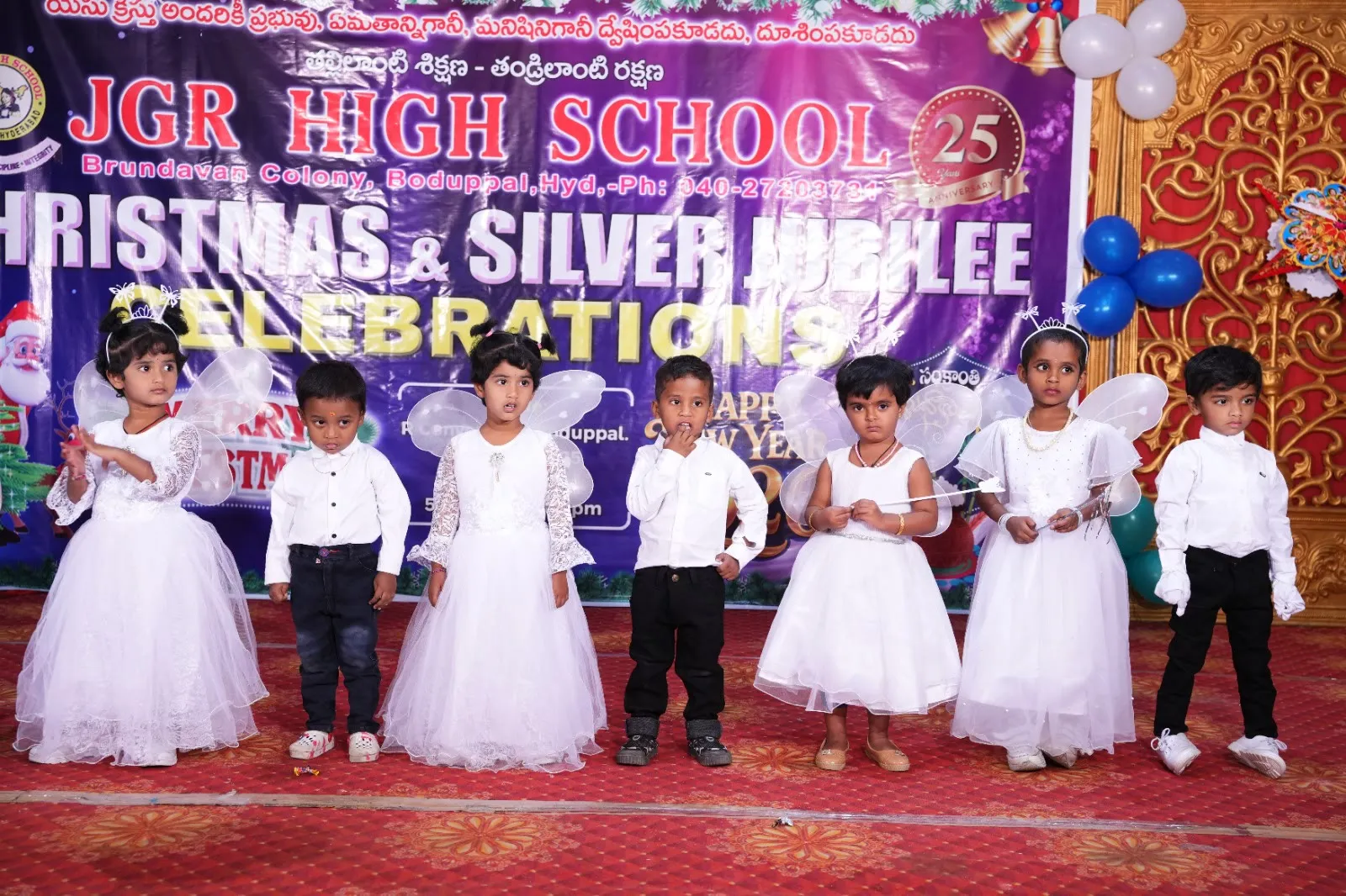 Pre-primary children in white angel costumes on stage at the Silver Jubilee